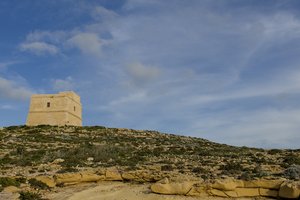 a tower standing alone in front of a blue sky 